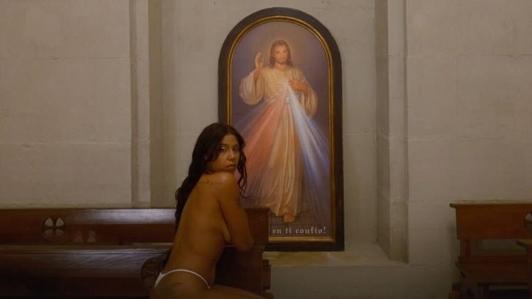 Tokischa semidesnuda frente a la imagen de la Divina Misericordia (Foto Instagram de la cantante)