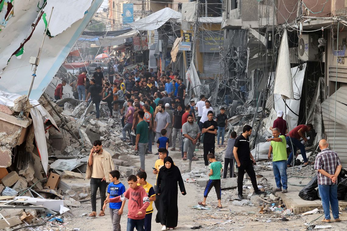 Palestinos caminan entre los escombros de edificios destruidos y dañados en el centro de la ciudad de Khan Yunis