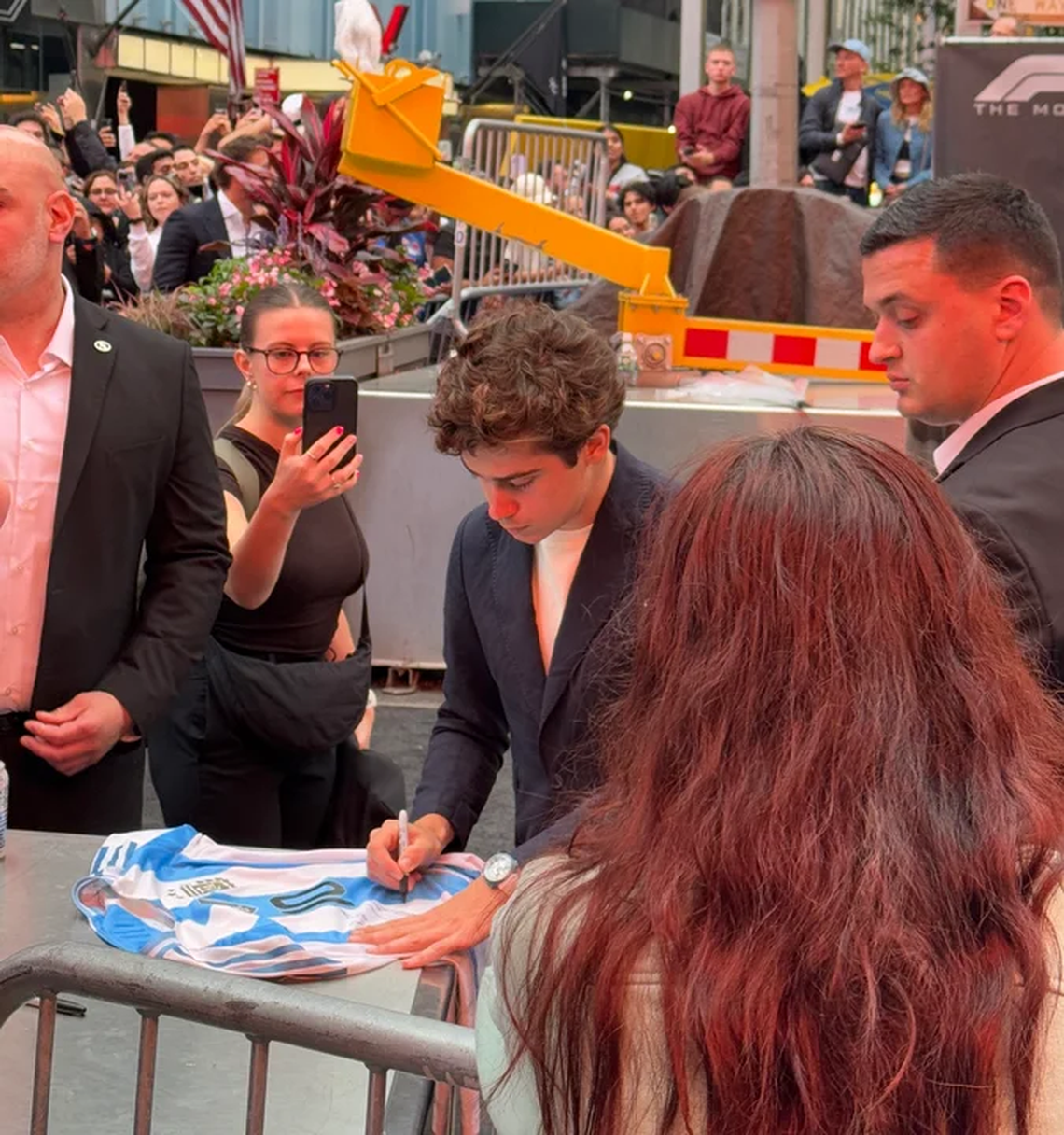 El piloto argentino Franco Colapinto firmando camisetas argentinas en el Times Square de Nueva York