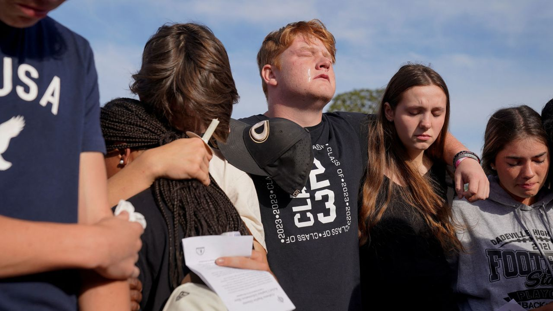 Los miembros de la comunidad se abrazan durante una vigilia por las víctimas del tiroteo en Dadeville, Alabama